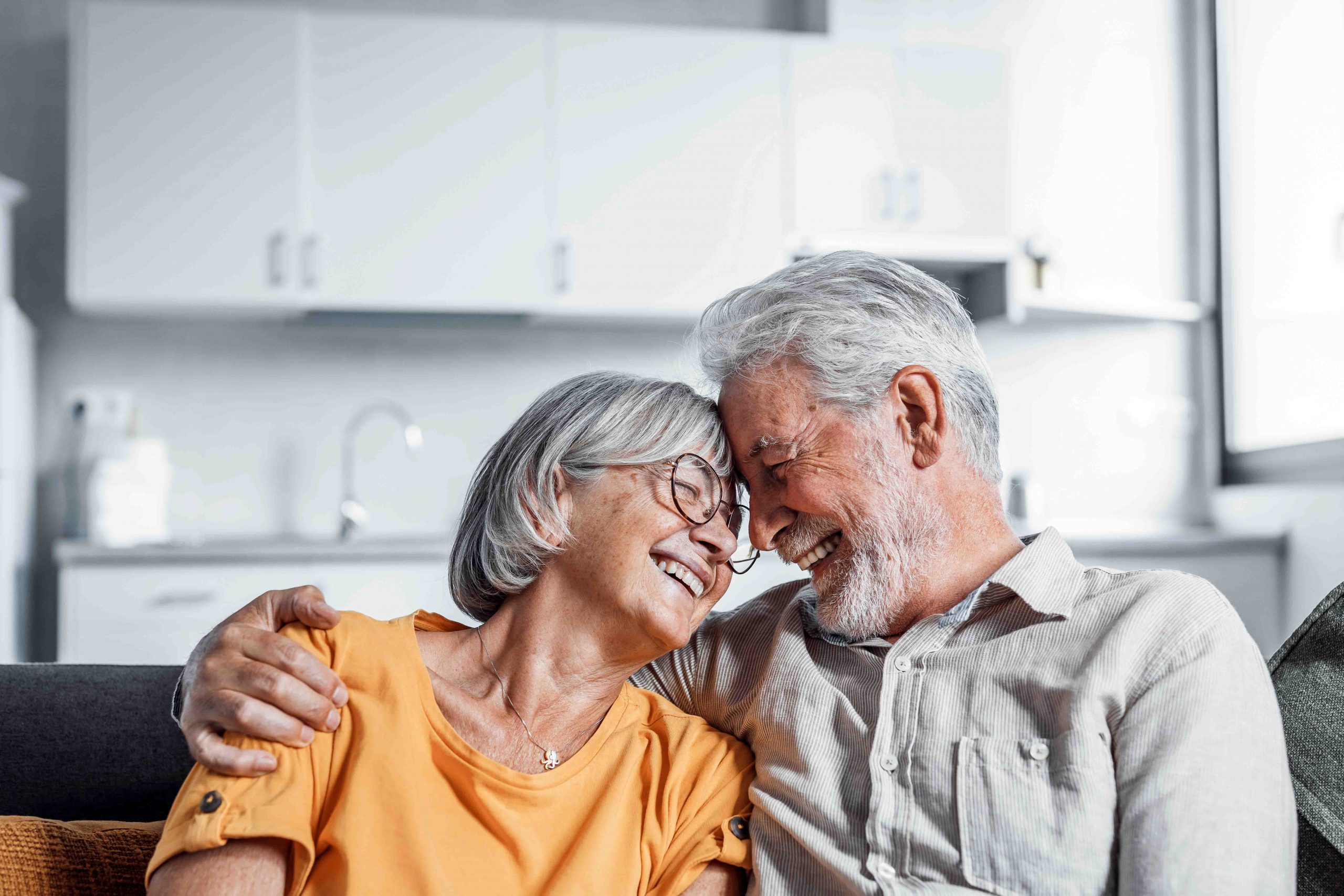 A joyful older couple embraces each other, their smiles reflecting a deep bond and affection in a heartwarming scene.