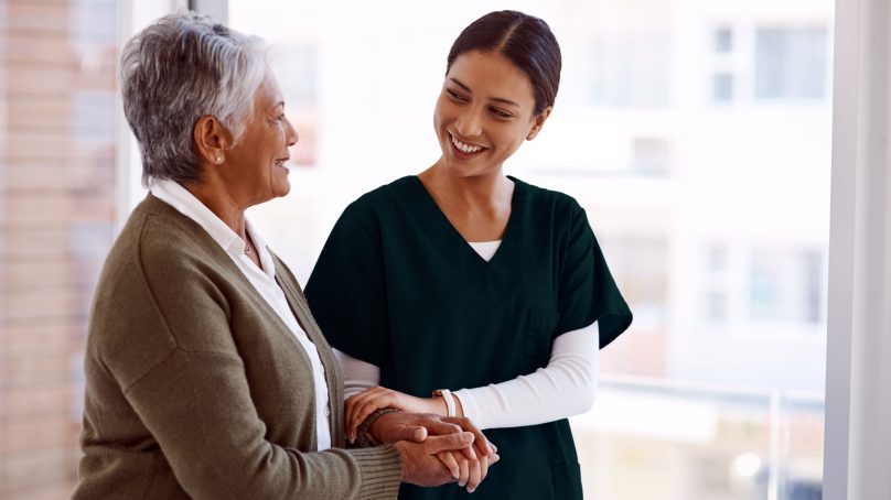 . A nurse shakes hands with an older woman, illustrating a moment of connection