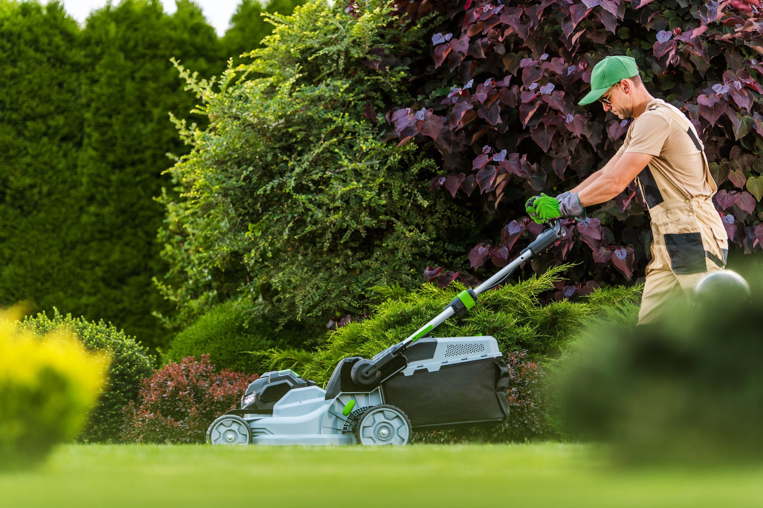 Garden Worker with lawn mower cutting residential grass