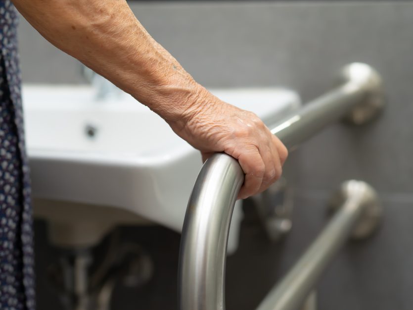 Senior Home Modifications - patient using toilet bathroom handle security in nursing hospital