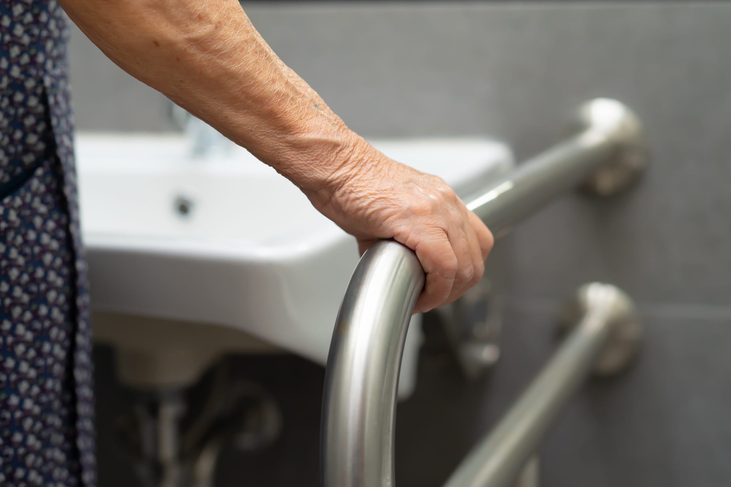 Senior Home Modifications - patient using toilet bathroom handle security in nursing hospital