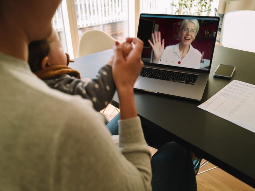 long-distance caregiving - A woman and child sit at a table with a laptop, engaged in long distance caregiving for aging in place.