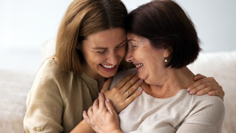 Mother and daughter laughing and hugging each other