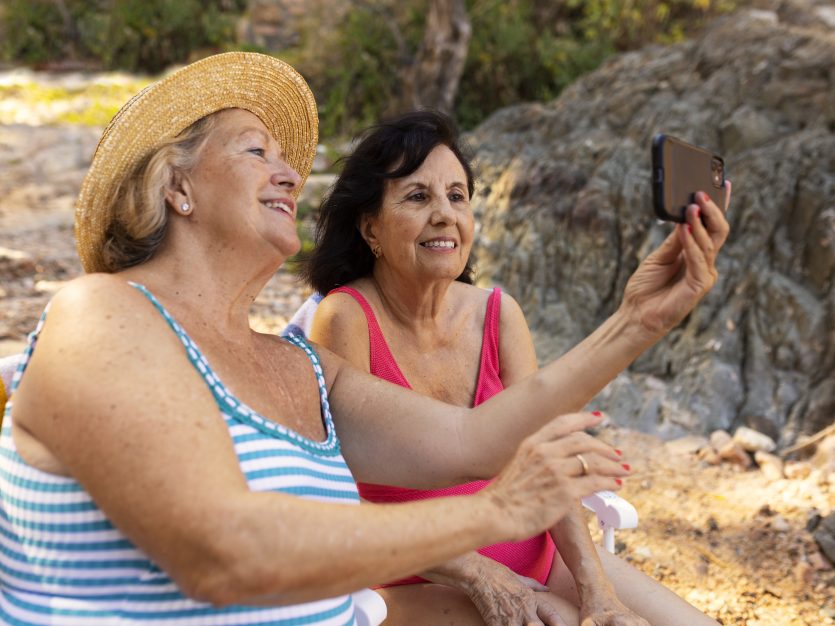 Two seniors clicking a selfie at the beach during summer vacation