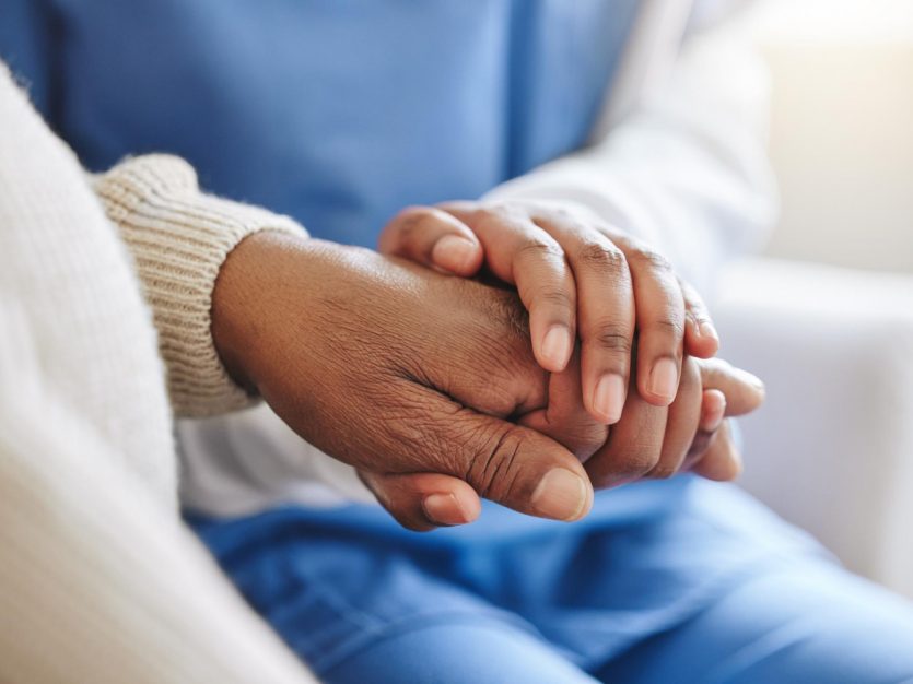 Nurse holding a senior's hand