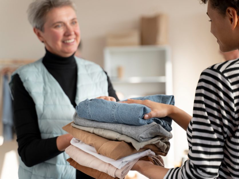 A woman handing a pile of folded clothes providing laundry services