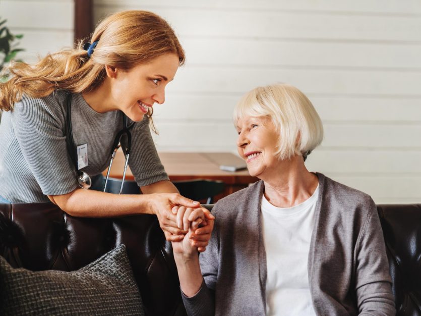 Caregiver holding the hand of a senior woman, providing companionship support.