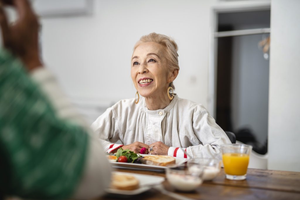 Meal Delivery - Lovely senior Japanese woman starting her day with lighthearted conversation and a delicious breakfast.