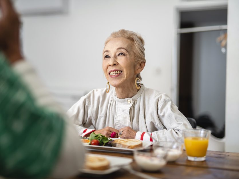 Meal Delivery - Lovely senior Japanese woman starting her day with lighthearted conversation and a delicious breakfast.