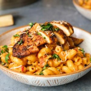 Cajun chicken with mac and cheese topped with herbs and grated parmesan cheese.