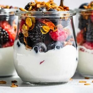 Mixed berry granola parfait in a glass cup.