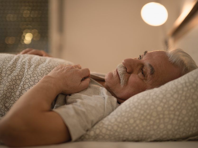 Sleep changes with age: Sleepless mature man thinking while lying down in bed in the evening.
