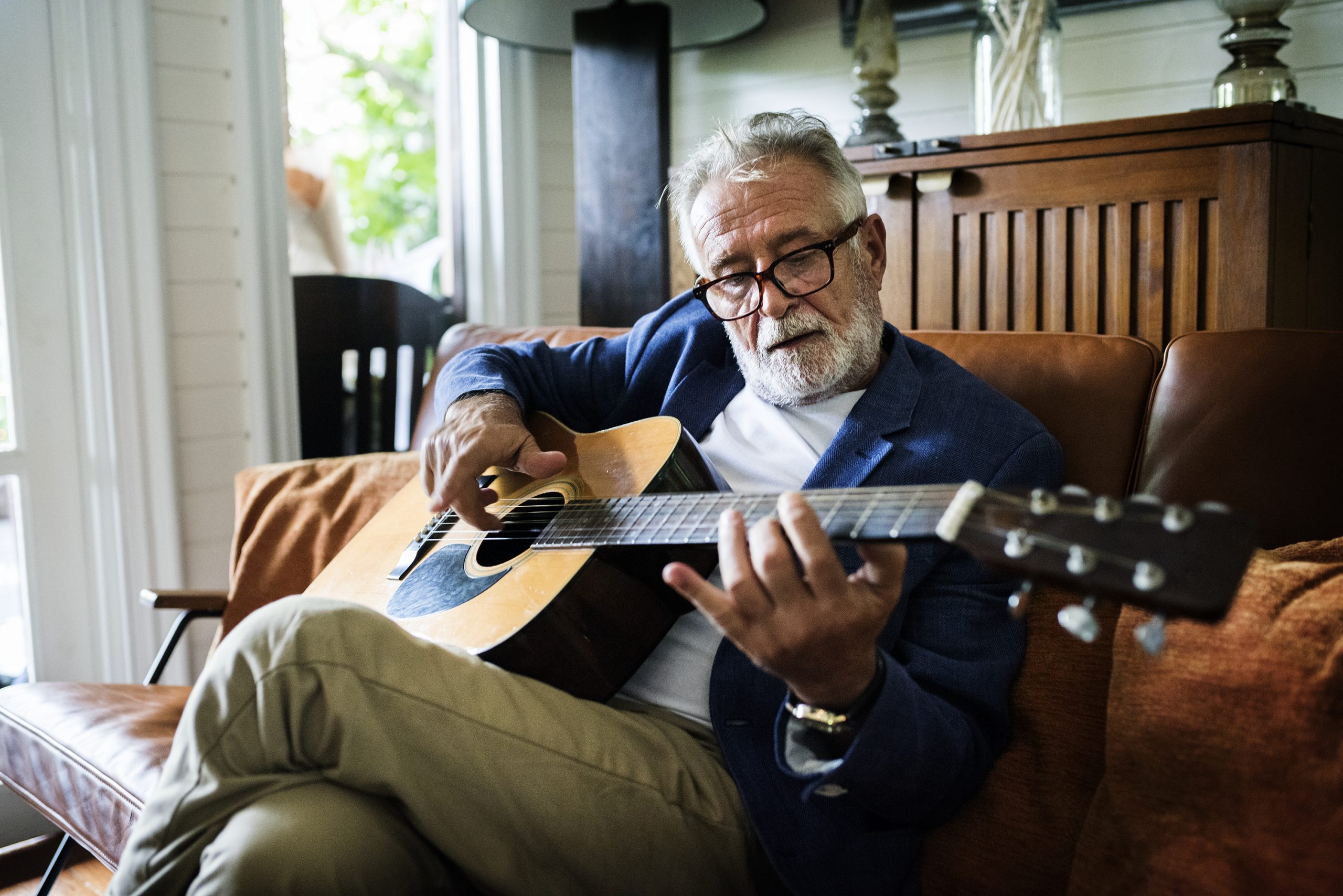 An elderly man is playing guitar