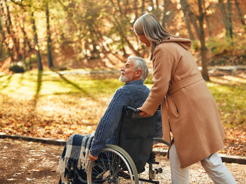 A Caregiver Joyfully Pushes A Senior In A Wheelchair