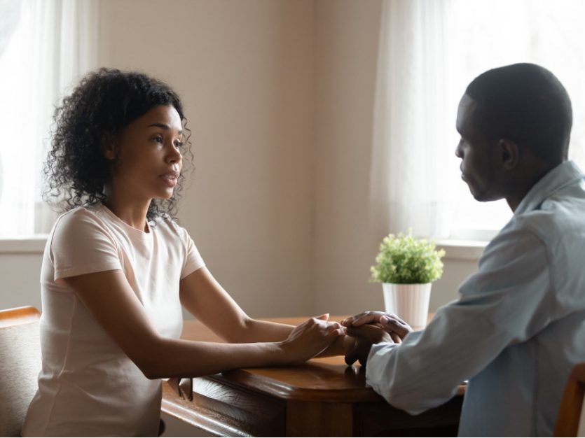 Sister and brother seated at a table in a cozy living room, engaged in conversation