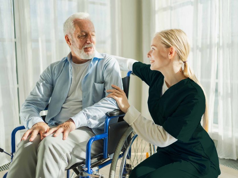 A woman assists an elderly man in a wheelchair, showcasing compassion and support at home.