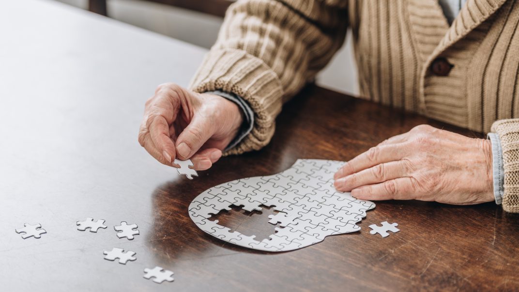 Coping strategies for memory loss 1 Senior man playing with a puzzle of an outlined head with missing pieces in the centre.
