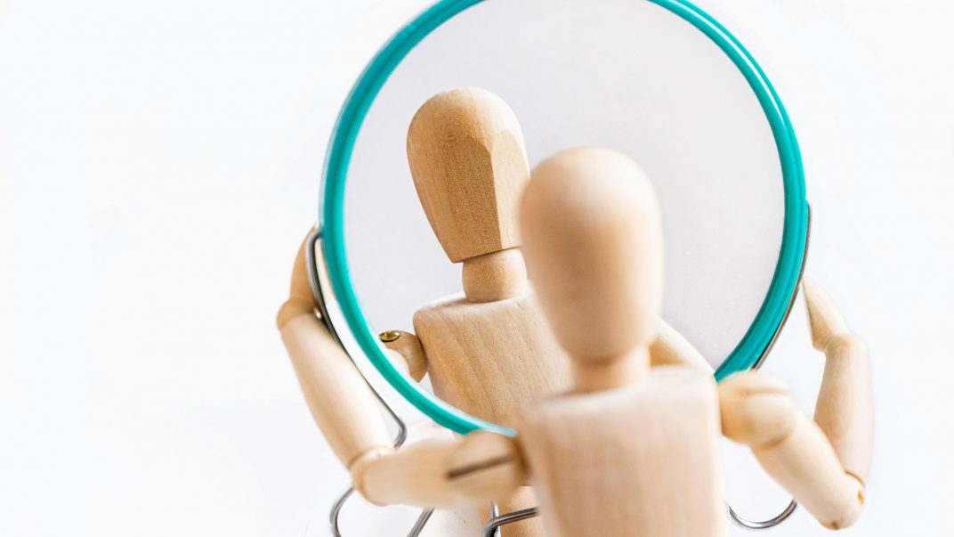 Understanding body dysmorphic disorder: It's not about vanity 1 a wooden figurine holding a round mirror