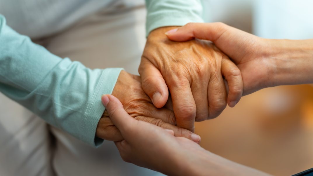 Alzheimer's care - Two hands holding each other gently.