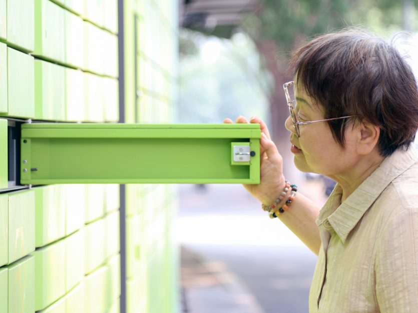 Older adult looking into opened mailbox.