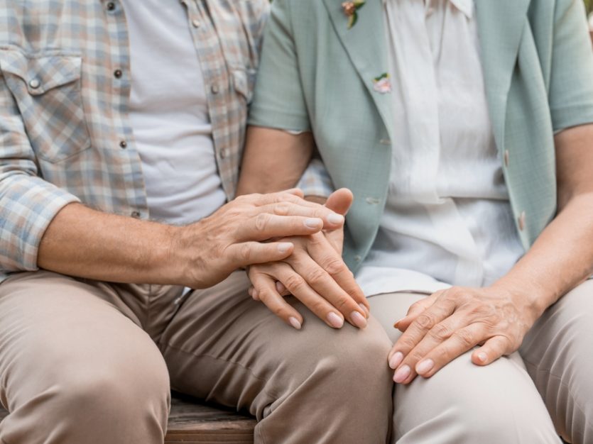 Senior couple holding hands on bench