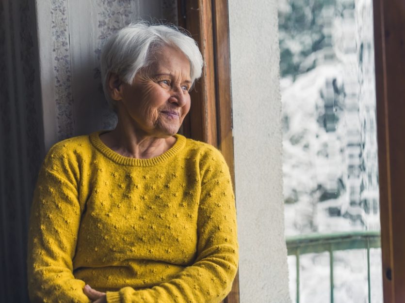Senior in yellow sweater by window - Supporting a Loved One Through the Winter Blues