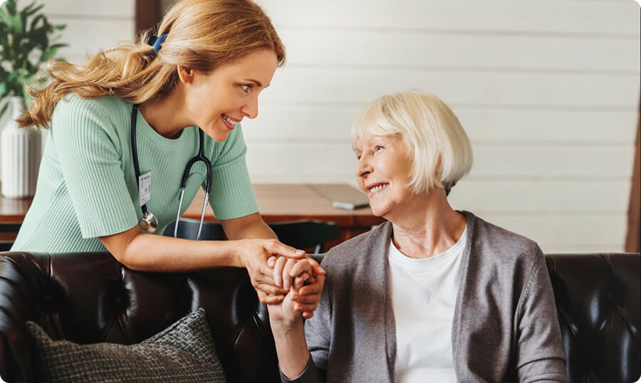 Nurse assisting elderly woman, smiling.