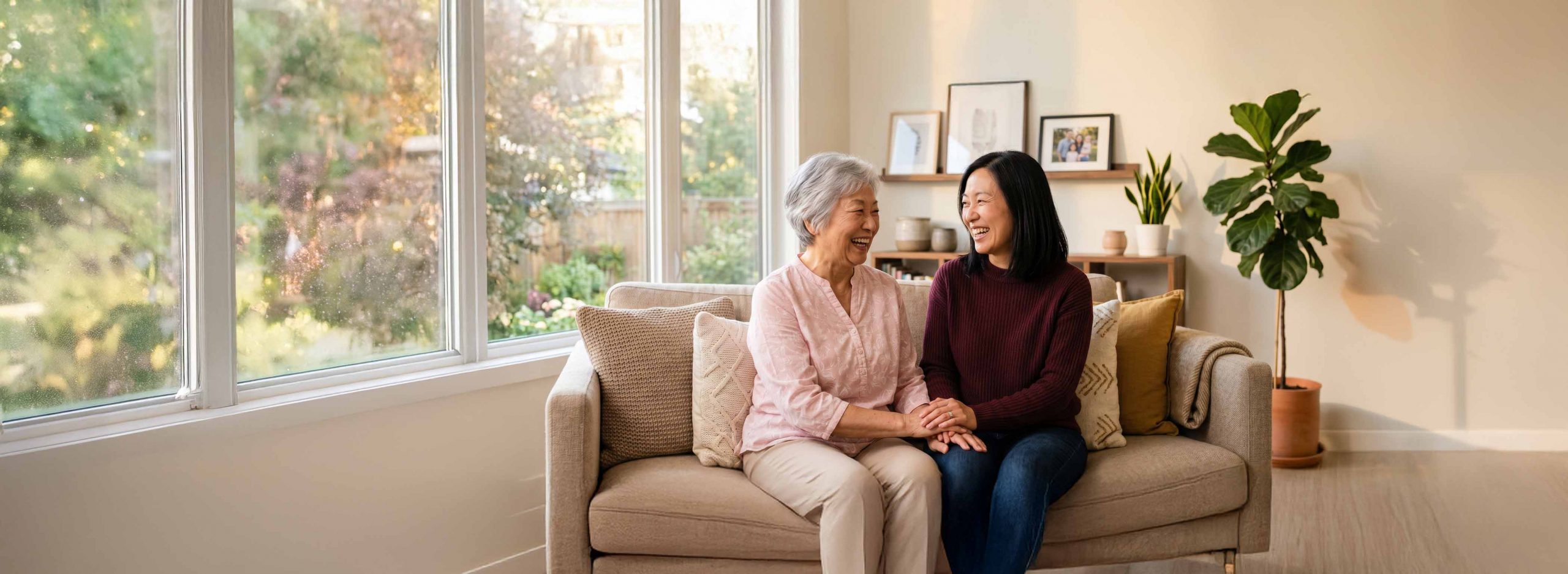 Elderly woman and daughter smiling while sat on a couch
