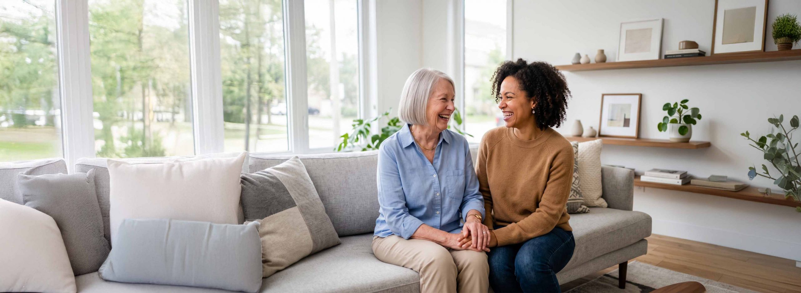 Elderly woman and daughter smiling while sat on a couch