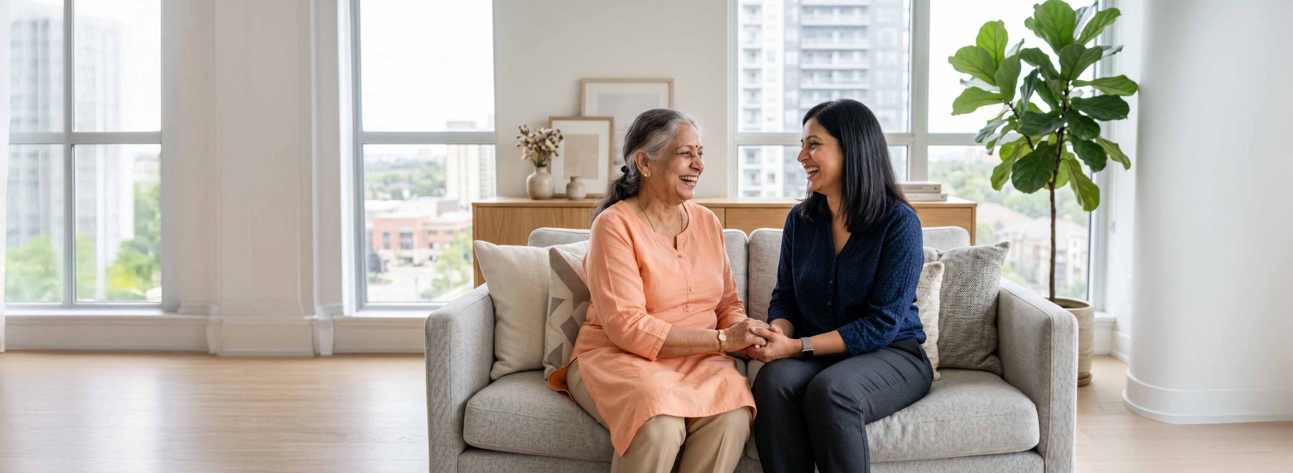 Elderly woman and daughter smiling while sat on a couch