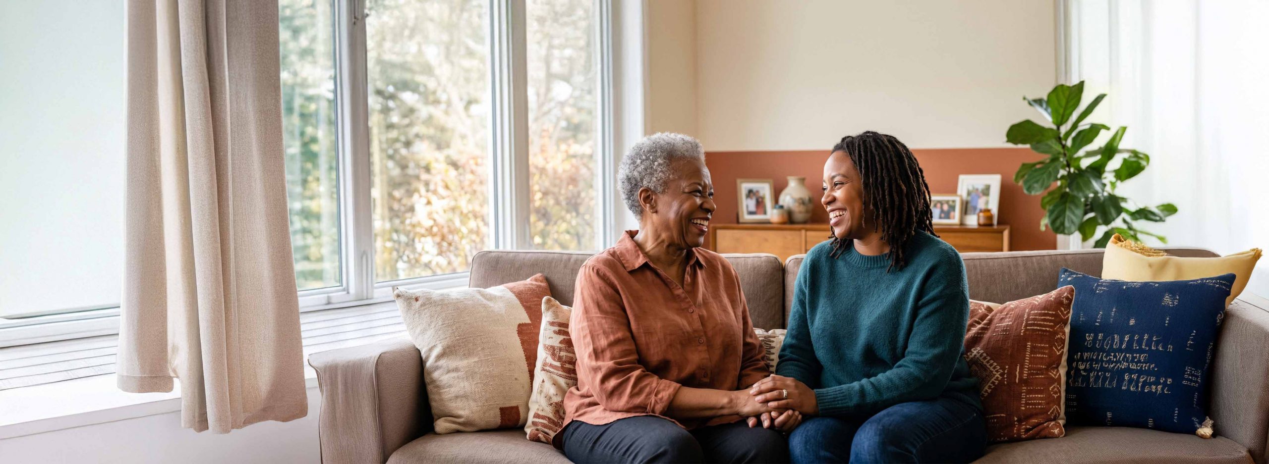 Elderly woman and daughter smiling while sat on a couch