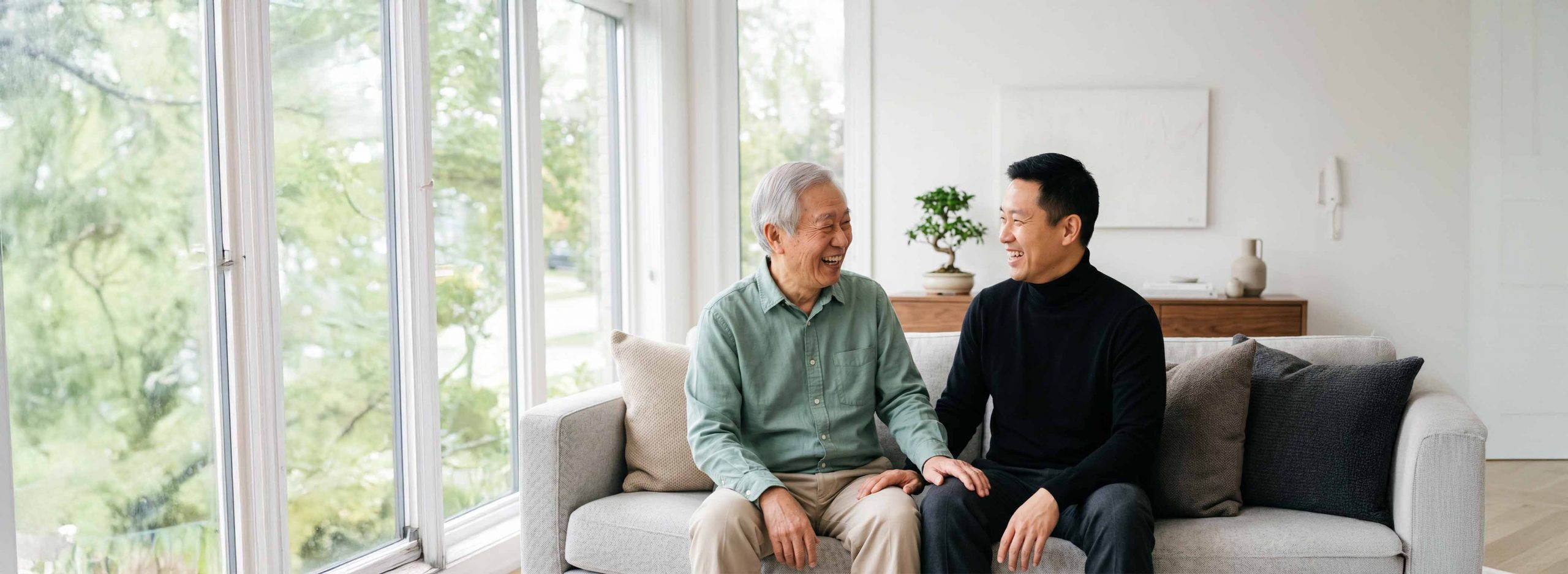 Elderly man and son sat on a couch