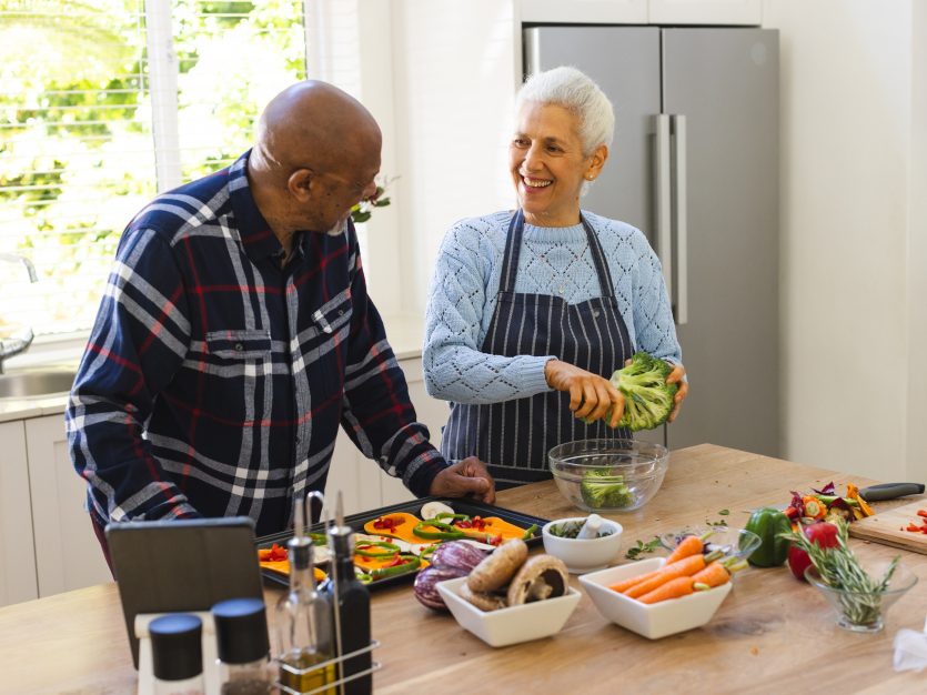 senior couple preparing healthy meal with vegetables in kitchen