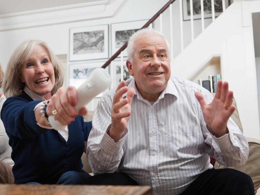 A group of older adults sitting on the couch and playing video games.
