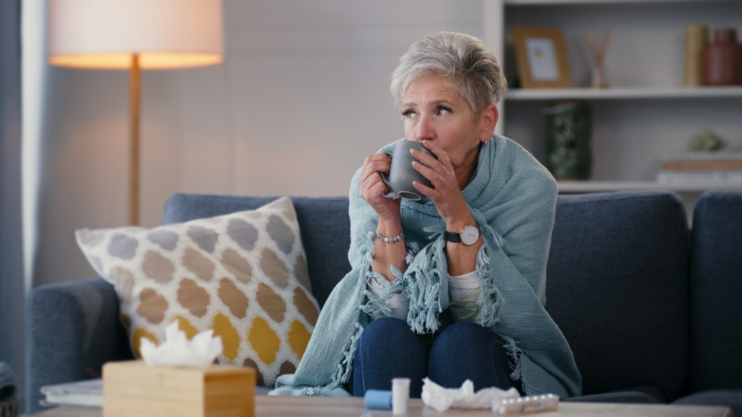 Cold and Flu Season: How to Be Prepared at Home 1 Woman sipping tea, cozy living room.